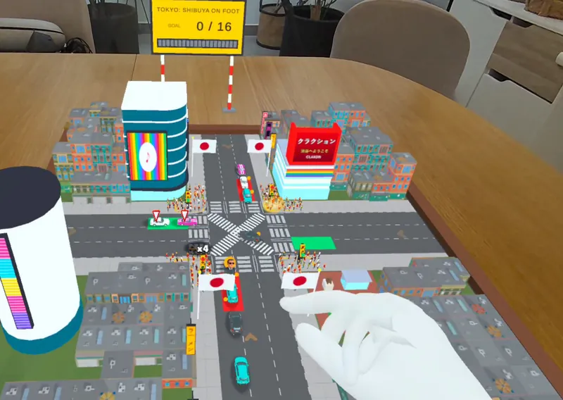 El cruce de Shibuya en miniatura sobre una mesa de verdad, con una mano abriendo un semáforo